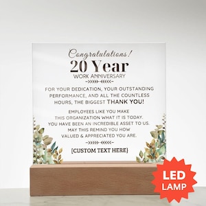 May include: A clear rectangular acrylic plaque featuring the text Congratulations! 20 Year WORK ANNIVERSARY, followed by a message of appreciation and a custom text placeholder. The plaque is decorated with watercolor leaves and sits on a wooden LED lamp base.