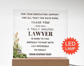 Könnte beinhalten: Eine klare Acrylplatte auf einem rechteckigen Holzsockel mit dem Text: FOR YOUR DEDICATION, SUPPORT AND ALL THAT YOU HAVE DONE, THANK YOU! A TRULY AMAZING LAWYER IS HARD TO FIND, DIFFICULT TO PART WITH AND IMPOSSIBLE TO FORGET. Links sind Schilf.