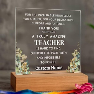 Può includere: Una targa in acrilico trasparente su una base rettangolare in legno. La targa presenta il testo stampato in bianco: FOR THE INVALUABLE KNOWLEDGE YOU SHARED, FOR YOUR DEDICATION, SUPPORT AND PATIENCE, THANK YOU! A TRULY AMAZING TEACHER IS HARD TO FIND, DIFFICULT TO PART WITH AND IMPOSSIBLE TO FORGET. Custom Name. Foglie ad acquerello incorniciano i lati.