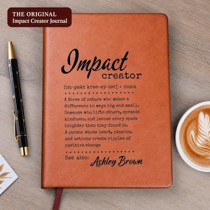 May include: A tan journal with black text that reads Impact creator [im-pakt kree-ey-ter] noun. A force of nature who makes a difference in ways big and small. Someone who lifts others, spreads kindness, and leaves every space brighter than they found it.