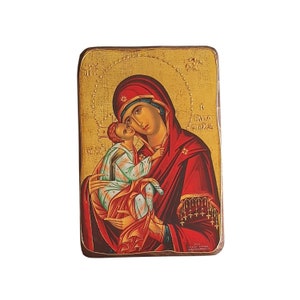 Può includere: Un'icona dipinta a mano che rappresenta la Vergine Maria che tiene in braccio il bambino Gesù. L'icona è dipinta su un pannello di legno con sfondo dorato e presenta uno schema di colori rosso e blu. Il testo "Η Θεοτόκος" è scritto in greco sul lato destro dell'icona.