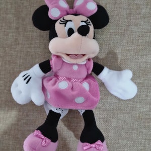 May include: Pink plush Minnie Mouse toy with white polka dots on her dress and bow. She has black shoes with pink bows.