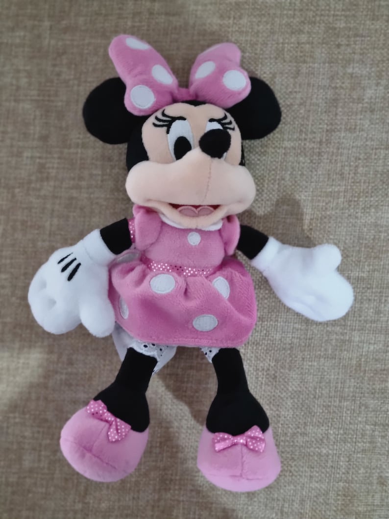 May include: Pink plush Minnie Mouse toy with white polka dots on her dress and bow. She has black shoes with pink bows.