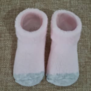 May include: A pair of pink fuzzy socks with gray bottoms.