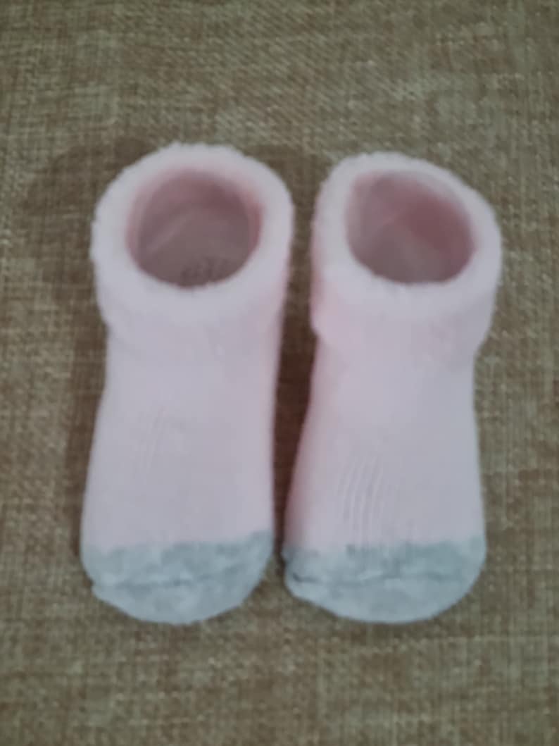 May include: A pair of pink fuzzy socks with gray bottoms.
