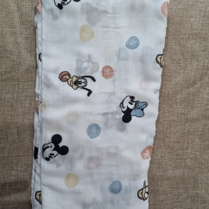May include: A white muslin baby blanket with a repeating pattern of colorful polka dots and cartoon images of Mickey Mouse and Pluto.