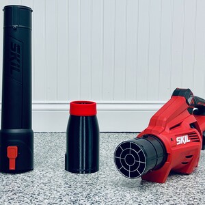 May include: A red and black cordless leaf blower with a black nozzle and a black and red extension nozzle. The leaf blower is made by SKIL.