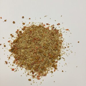 Può includere: Primo piano di un mucchio di erbe e spezie secche, tra cui zenzero, curcuma e fiocchi di peperoncino rosso. Le spezie sono un mix di marrone chiaro, giallo e arancione.