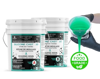 Könnte beinhalten: Zwei weiße Eimer mit Silikon-Gießharz, beschriftet mit "Silicone Cast 30", wobei ein grüner Eimer das Harz in einen Behälter gießt. Der grüne Eimer trägt ein Etikett mit der Aufschrift "Food Grade".