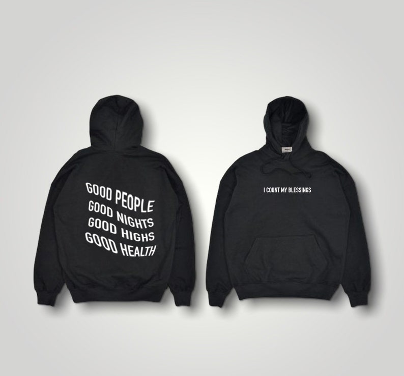 K&ouml;nnte beinhalten: Zwei schwarze Kapuzenpullover. Einer hat den wei&szlig;en Aufdruck "GOOD PEOPLE GOOD NIGHTS GOOD HIGHS GOOD HEALTH" auf dem R&uuml;cken. Der andere hat "I COUNT MY BLESSINGS" in Wei&szlig; auf der Vorderseite.