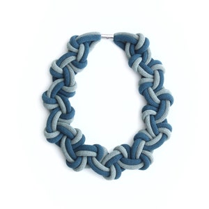 Puede incluir: Un collar azul y gris anudado hecho de cuerda de tela. El collar es un c&iacute;rculo y tiene un cierre plateado.
