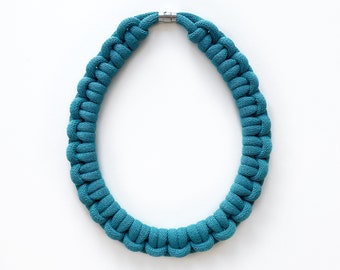 Op de afbeelding: Een teal blauwe paracord ketting met een zilveren sluiting.