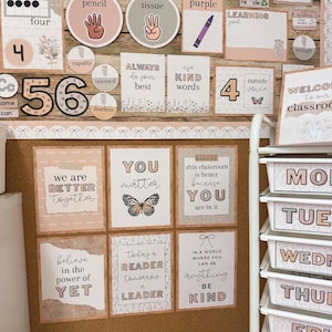 May include: A classroom bulletin board display featuring educational posters, number charts, and motivational signs in a neutral color palette. The decor includes text-based prints, butterfly illustrations, and a white rolling cart with labeled drawers.