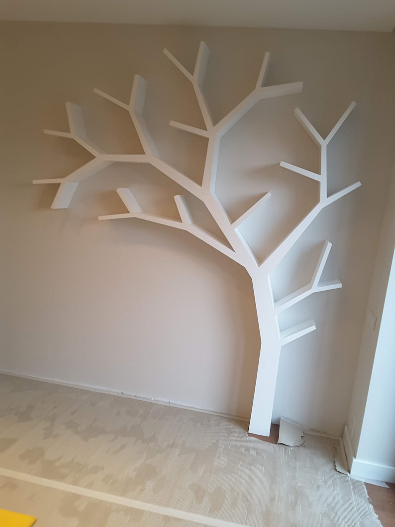 Pu&ograve; includere: Una mensola a muro bianca a forma di albero. La mensola &egrave; montata su una parete beige e ha diversi rami che fungono da ripiani. Il design &egrave; moderno e minimalista, adatto per esporre libri o oggetti decorativi.