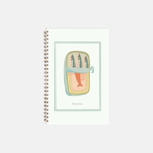 May include: Spiral-bound notebook with a sardine can illustration. The can is open, showing three fish. The notebook has a white background, a green border, and the words "le poisson". The notebook is ideal for notes.