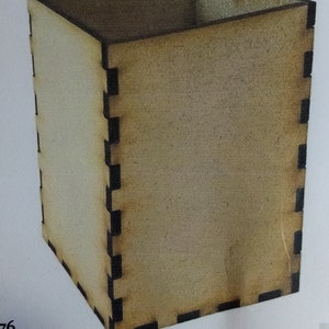 May include: A square wooden box with a natural wood finish. The box is constructed with interlocking joints, creating a clean and modern aesthetic. The edges are dark, contrasting with the lighter wood. This box could be used for storage or display.