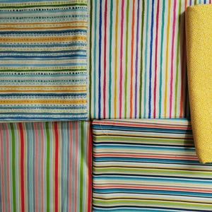 May include: A selection of fabric samples with diverse striped patterns. The fabrics display stripes in blue, green, yellow, red, and orange. One fabric is plain yellow with a geometric design.