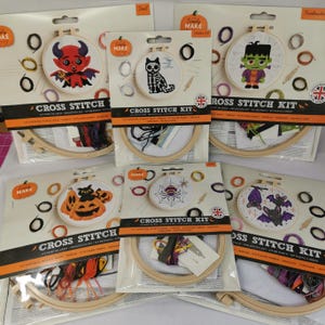 May include: A collection of Halloween cross-stitch kits. Designs include a devil, a skeleton cat, Frankenstein's monster, pumpkins, a spider web, and bats. Each kit contains a wooden hoop, fabric, thread, and instructions.