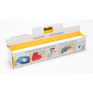 May include: A yellow and white box with the text "Vliesofix® // Bondawweb®" and "Iron-on Adhesive" on it. The box contains a roll of iron-on adhesive for fabric crafts.