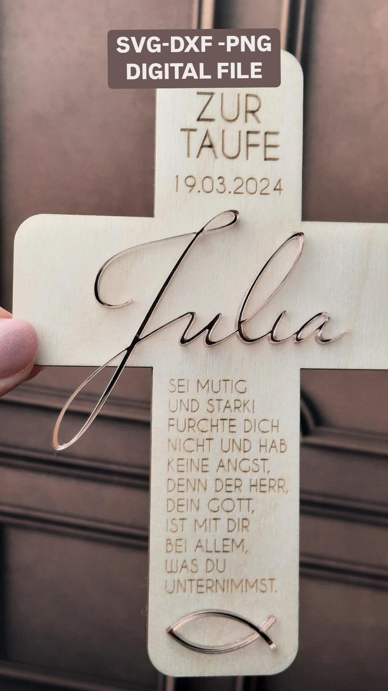 May include: A wooden cross with the name "Julia" engraved on it. The cross is decorated with a small fish symbol and a message in German that reads "Sei mutig und stark! Furchte dich nicht und hab keine Angst, denn der Herr, dein Gott, ist mit dir bei allem, was du unternimmst." The date "19.03.2024" is also engraved on the cross.