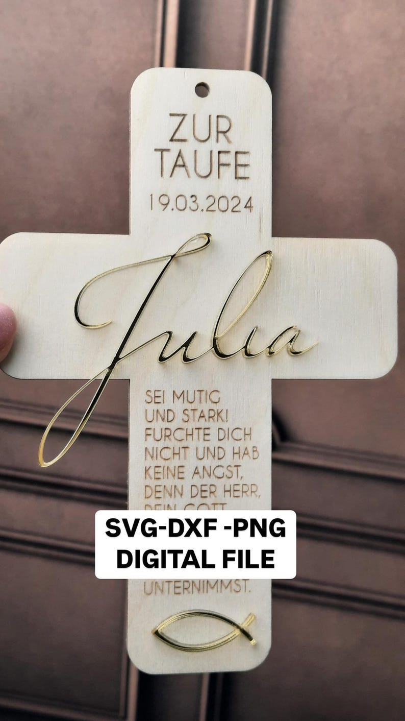 May include: A wooden cross with the name "Julia" engraved in gold lettering. The cross also features the text "Zur Taufe 19.03.2024" and a quote in German: "Sei mutig und stark! Furchte dich nicht und hab keine Angst, denn der Herr, dein Gott unternimmst."