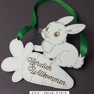 Puede incluir: Conejo blanco sentado en una zanahoria blanca con el texto "Herzlich Willkommen" en marrón. La zanahoria tiene hojas verdes. El conejo tiene ojos marrones y una nariz rosa. La imagen está sobre un fondo gris.