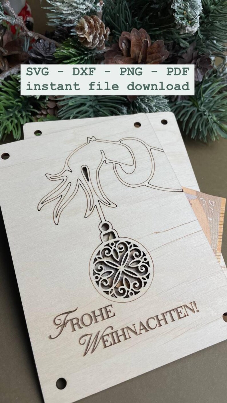 May include: A wooden Christmas ornament with a cut-out design of a Christmas tree and ornament. The ornament is light brown and has the text "Frohe Weihnachten!" on the bottom.