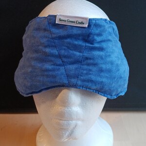 May include: A blue eye mask made from textured fabric, displayed on a white mannequin head. The mask features a label that says "Sewn Green Crafts". The mask is designed to cover the eyes and forehead.