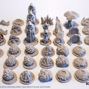 Könnte beinhalten: Eine Sammlung grauer Miniatur-Spielgeländeteile, darunter Kapuzenfiguren, Bäume und verschiedene strukturierte Sockel. Die Teile sind für Tabletop-Spiele konzipiert und auf einer weißen Oberfläche angeordnet. Das Board Game Plus Logo ist sichtbar.