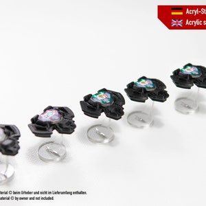 May include: Six clear acrylic stands with black bases holding colourful miniature game pieces. The stands are arranged in a row on a white surface.