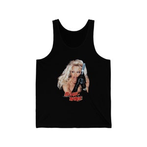 May include: Black tank top featuring a graphic of Pamela Anderson from the film "Barb Wire". The graphic depicts her holding a gun and wearing a black leather glove. The text "Barb Wire" is in red.