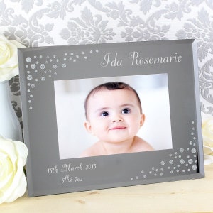 K&ouml;nnte beinhalten: Ein grauer Glas-Bilderrahmen mit silbernen Glitzerakzenten. Der Rahmen enth&auml;lt ein Foto eines Babys mit dem Text "Ida Rosemarie" und "16th March 2015 6lbs 7oz" darauf.