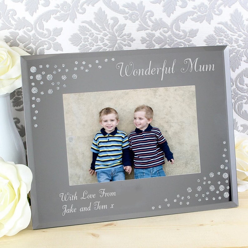 K&ouml;nnte beinhalten: Ein grauer Bilderrahmen mit einem silbernen Glitzerdesign an den R&auml;ndern. Der Rahmen tr&auml;gt die Worte "Wonderful Mum" oben und "With Love From Jake and Tom x" unten. Der Rahmen enth&auml;lt ein Foto von zwei jungen Jungen.