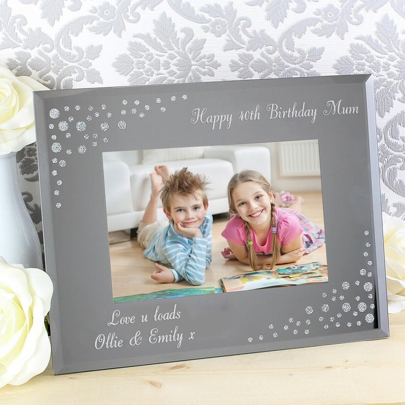 K&ouml;nnte beinhalten: Ein grauer Bilderrahmen mit einem silbernen Glitzerrand und einem Foto von zwei Kindern. Der Rahmen tr&auml;gt den Text "Happy 40th Birthday Mum" und "Love u loads Ollie & Emily x" eingraviert.