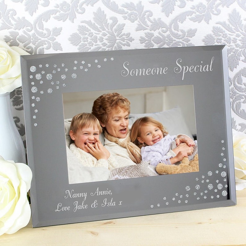 K&ouml;nnte beinhalten: Ein grauer Bilderrahmen mit einem silbernen Glitzerrand und den Worten "Someone Special" oben. Der Rahmen enth&auml;lt ein Foto einer Gro&szlig;mutter und zweier Enkelkinder. Die Inschrift unten lautet "Nanny Annie, Love Jake & Isla x".