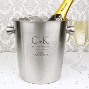 May include: Silver champagne bucket with engraved initials "C.K." and the text "11th Anniversary 21st June 2018".