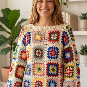 May include: Cream-colored crochet sweater with colorful square patterns. The sweater features a crew neck and long sleeves with a patchwork design of red, blue, yellow, and green squares. A cozy, handmade garment.