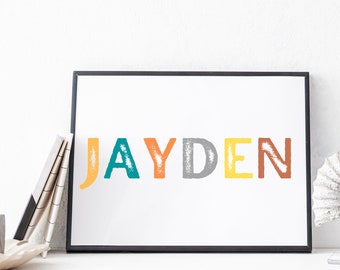 May include: A framed print with the name "JAYDEN" in colorful, textured letters. The letters are in shades of orange, teal, gray, yellow, and brown against a white background. The frame is black, and the print is displayed on a white surface.