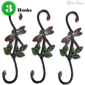 May include: Set of three cast iron hooks featuring a dragonfly design with green leaves. The hooks are black with brown accents.  "3 Hooks" is written on the image.