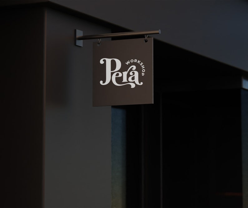 May include: A black sign with white text that reads "Pera Workshop" hanging on a dark brown wall.