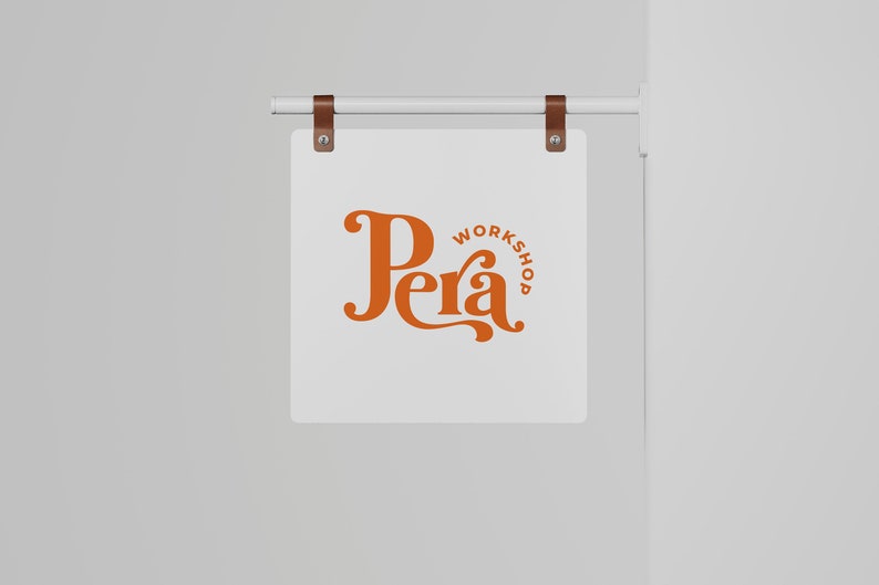 May include: A white sign with brown leather straps hanging from a white metal rod. The sign has the text "Pera Workshop" in orange lettering.