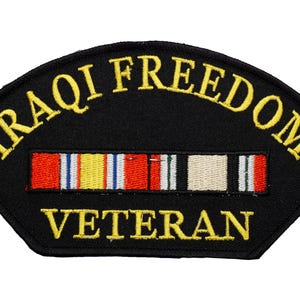 May include: Black embroidered patch with gold lettering that reads "IRAQI FREEDOM VETERAN". A ribbon with red, white, yellow, and green stripes is sewn below the text.