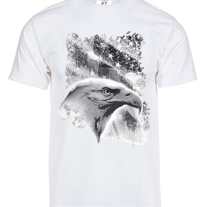 Pode incluir: Camiseta branca com uma estampa gráfica em preto e branco de uma cabeça de águia com uma bandeira americana desbotada no fundo.