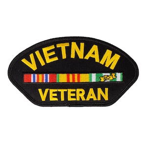 May include: Black embroidered patch with yellow text that reads "VIETNAM VETERAN". A row of colorful ribbons is sewn above the text.