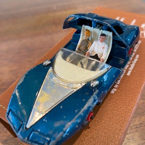 May include: A blue toy car with a white interior and a removable roof. Two small figures are sitting in the car. The car is made by San Francisco.