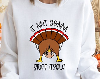 May include: White sweatshirt with a funny Thanksgiving turkey graphic. The turkey is bending over with the text "It ain't gonna stuff itself".