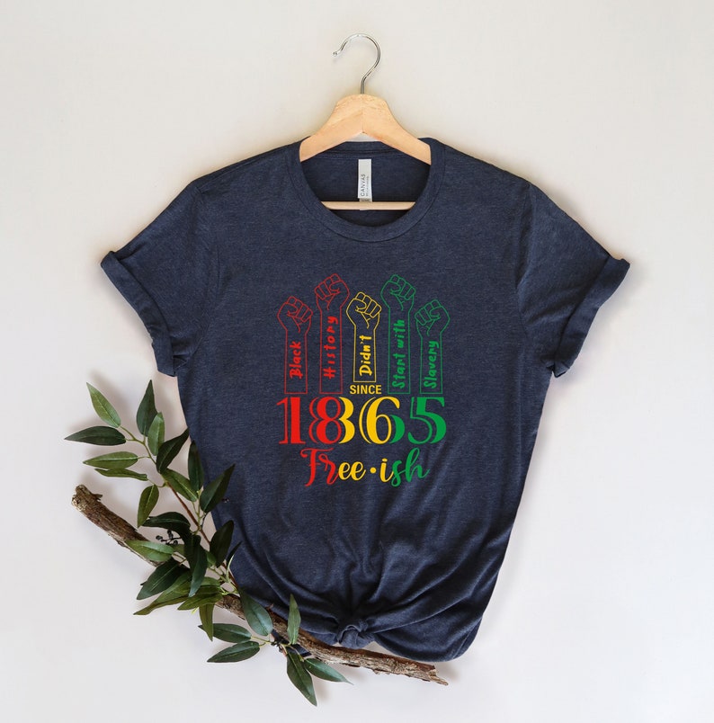 May include: A dark blue t-shirt with a graphic design featuring raised fists with the text "Black History Didn't Start with Slavery" and the year "1865" with the text "Free-ish" below.