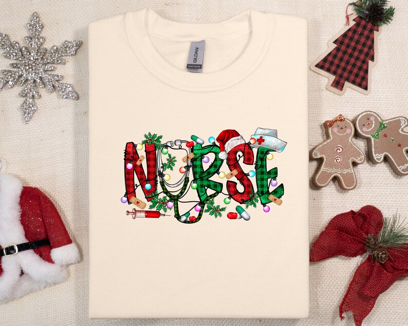 May include: A cream-colored t-shirt with a Christmas-themed design featuring the word "NURSE" in green, red, and white plaid with a stethoscope, candy canes, and Christmas lights.