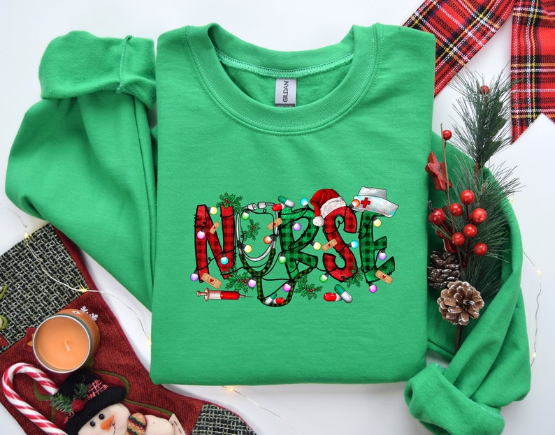 May include: Green Christmas themed sweatshirt with the word "NURSE" in red, white, and green plaid with a stethoscope, candy canes, and a Santa hat.