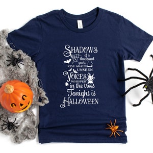 K&ouml;nnte beinhalten: Ein marineblaues T-Shirt mit einer wei&szlig;en Grafik, auf der steht "Shadows of a thousand years rise again unseen voices whisper in the trees tonight is HALLOWEEN".